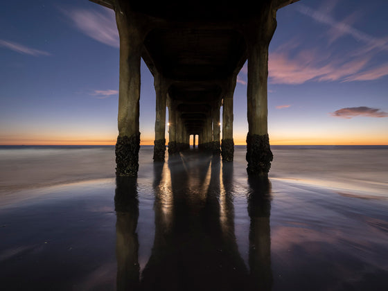 Manhattan Beach pier photo taken from underneath the pier ,after sunset during the blue hour. This is a long exposure and the sky is ombre above the horizon.