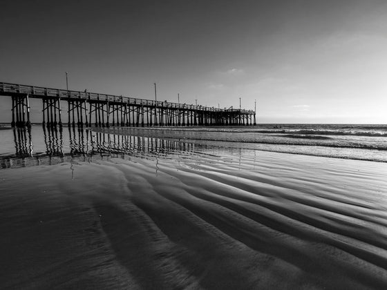 Newport Beach pier at low tide, with ripples of sand, in black and white