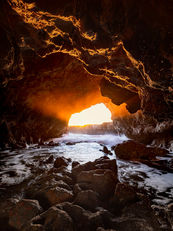 A cave in Palos Verdes California, low tied, sunset, with light rays streaming in and the ocean mist illuminated by the setting sun