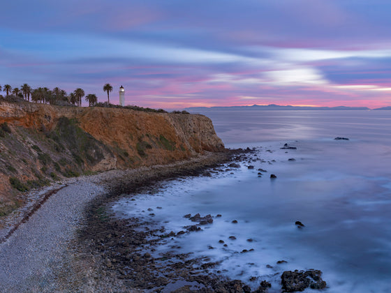 The palos verdes vicente lighthouse during sunset with pink clouds and calm water.