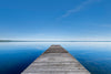 a dock on a calm, still lake with blue water and blue skies