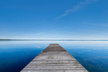  a dock on a calm, still lake with blue water and blue skies