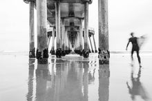  surfer under the huntington beach California pier, in black and white