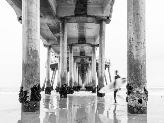 surfer under the huntington beach California pier, in black and white