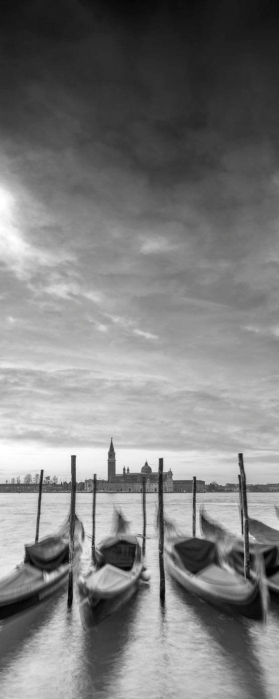 Black and white vertical panoramic photo of gondolas and the Church of San Giorgio Maggiore, on the Grand Canal in Venice Italy